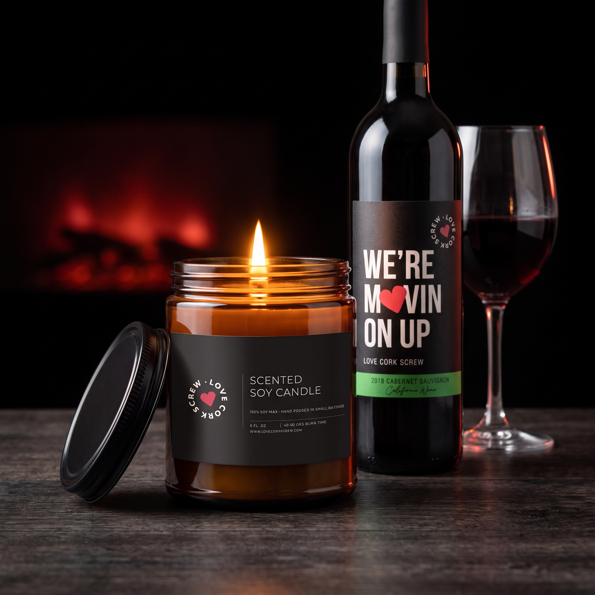 Love Cork Screw 9oz soy candle lit beside We're Movin' On Up Cabernet and a glass of red wine